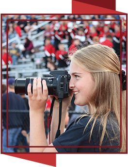 Student holding a camera at an event