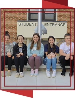 Group of happy students sitting on the curb outside the Student Entrance
